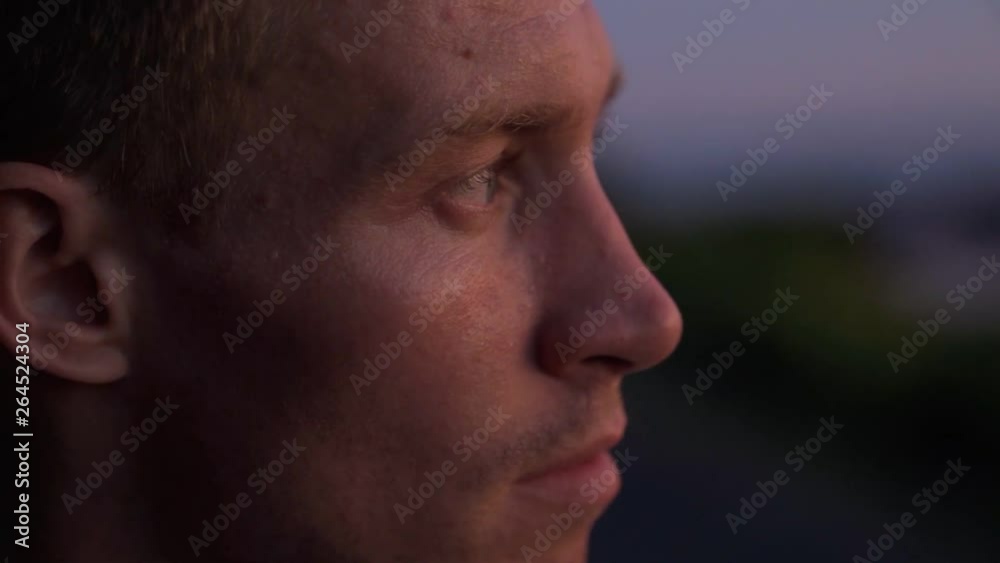 Close up portrait of brutal blue eyed blond guy watching sunset on beach. Evening time. Slow motion Close up portrait of brutal blue eyed blond guy watching sunset on beach. Evening time. Slow motion