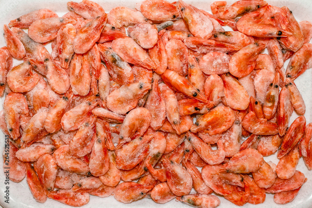 Raw shrimp background. Pile of frozen shrimps on white background.Close-up of frozen shrimps. Shrimp and ice, top view. Raw shrimp background. Pile of frozen shrimps on white background.Close-up of frozen shrimps. Shrimp and ice, top view.