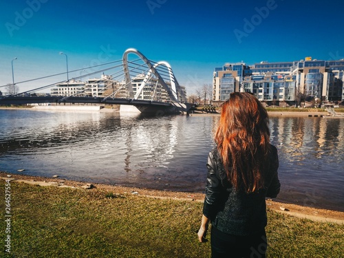 Photography Brunette girl with long hair in a jacket stands on the background of Modern arch