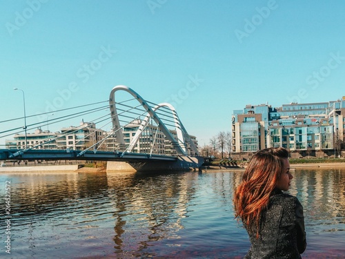 Photography Brunette girl with long hair in a jacket stands on the background of Modern arch