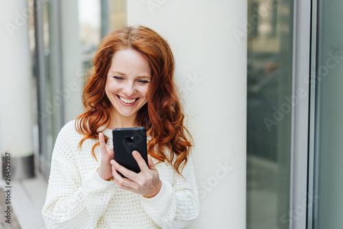 Happy young woman reading a text message