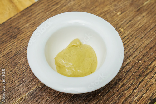 Mustard in a white Cup on a cutting Board
