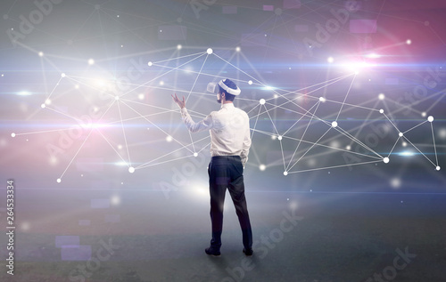 Young businessman standing with vj glasses and checking life-sized connectivity project  