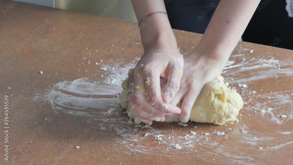 Female hands kneading dough in flour on table Female hands kneading dough in flour on table