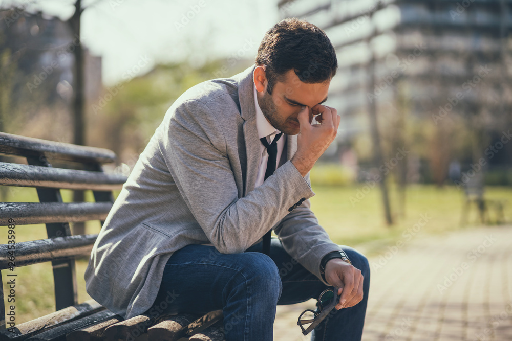 Fototapeta premium Young businessman is very tired. He is relaxing in park. 