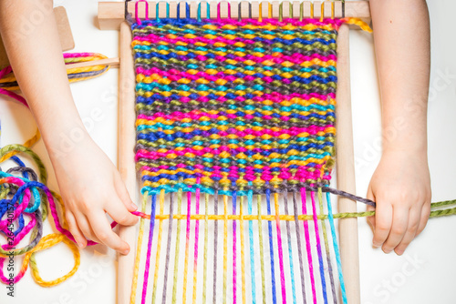 Weaving. Hands of little caucasian girl working on small loom weaving.