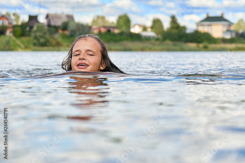 Smiling teenage girl swims in russian suburban lake in summer