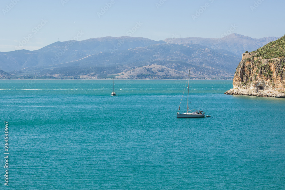 south European sea bay scenery landscape landscape in Greece Mediterranean coast line with ship on calming vivid blue water surface and mountain background 