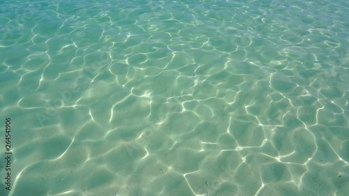 relaxing on the beach. Summer vacations, idyllic scene. Pure blue water in the sea with light reflections. Slow motion. on summer holiday