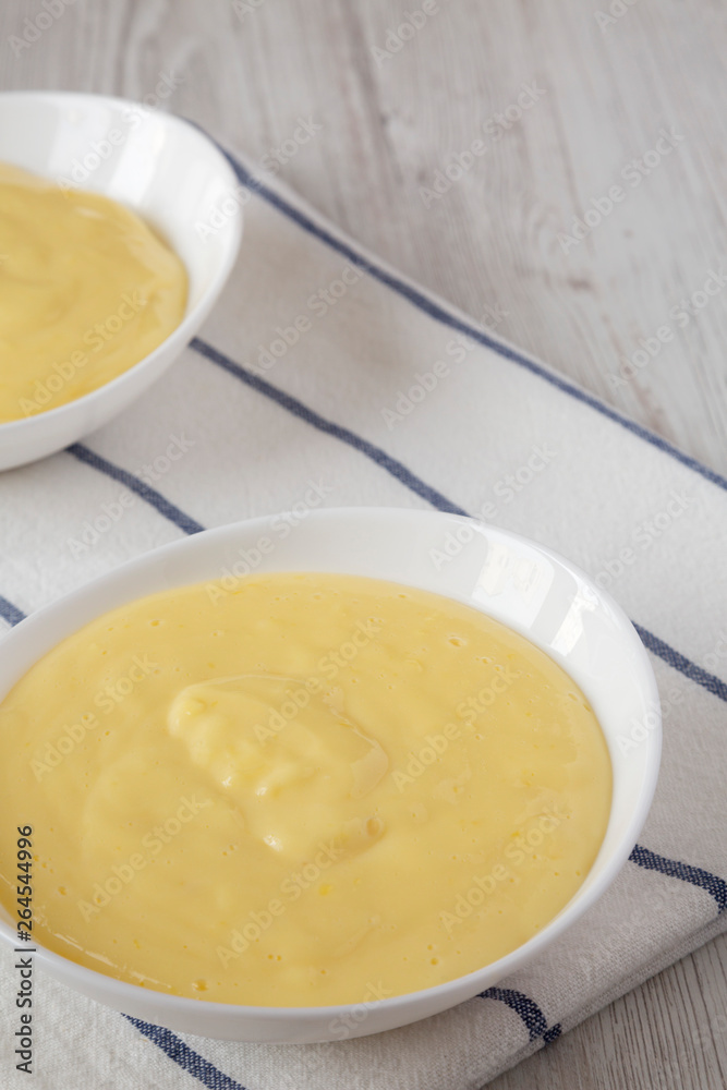 Homemade vanilla custard pudding in white bowls, low angle view. Space for text. Homemade vanilla custard pudding in white bowls, low angle view. Space for text.