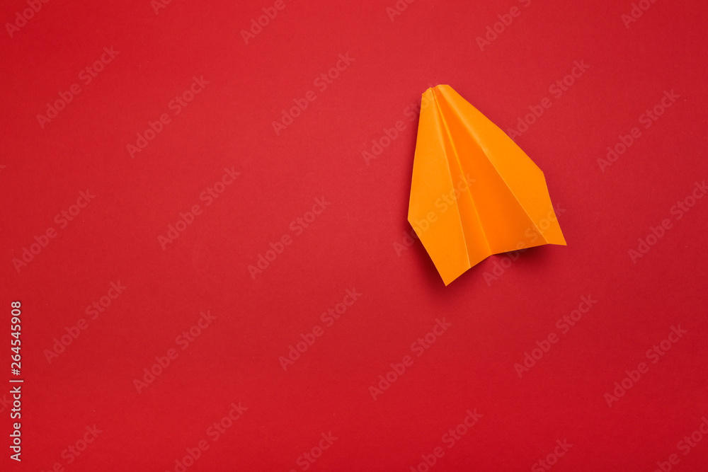 Flat lay of colour paper plane on red background with text space.