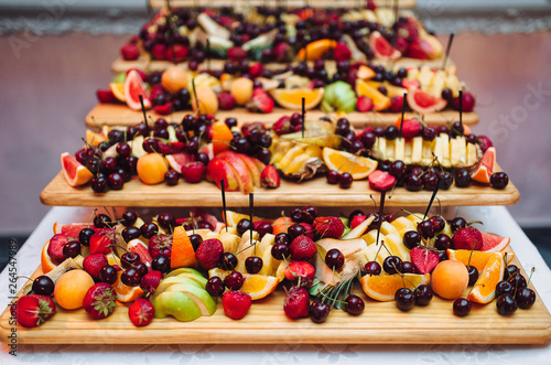 Wedding and festive buffet. Buffet of various fresh fruits on wooden shelves. Strawberry, orange, cherry, banana, apple, pear, grapefruit.