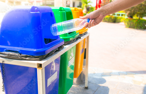 Man hand throwing plastic in recycling bin to help environmental protection and Waste separation reduce global warming.