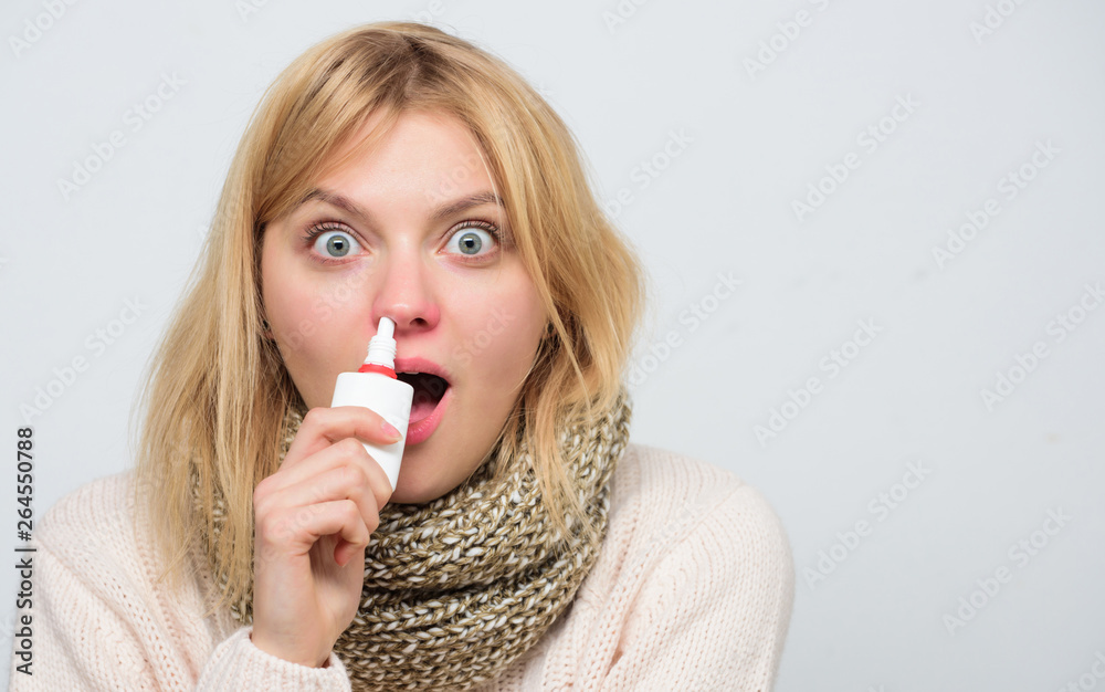 Treating her symptoms. Sick woman spraying medication into nose. Cute woman nursing nasal cold or allergy. Unhealthy girl with runny nose using nasal spray. Treating common cold or allergic rhinitis Treating her symptoms. Sick woman spraying medication into nose. Cute woman nursing nasal cold or allergy. Unhealthy girl with runny nose using nasal spray. Treating common cold or allergic rhinitis