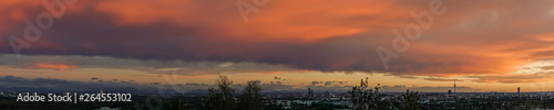 panoramic view taken at sunset over munich city in bavaria, germany with dramatic cloudy sky and mountains in background