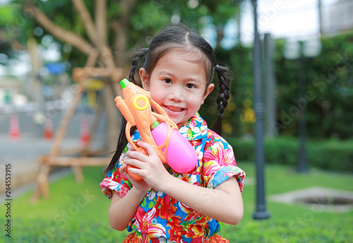 Cheerful kid girl playing water gun at Songkran festival on summer season in thailand  Thai new year - water festival .
