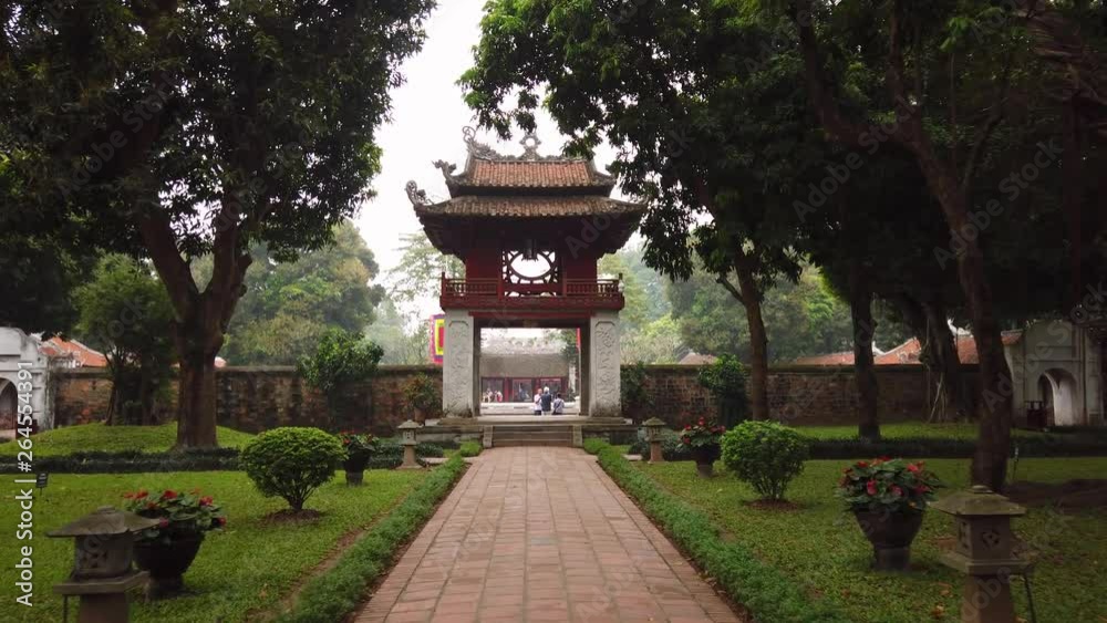 Gimbal forward Temple of Literature Hanoi Vietnam. Ancient historical old complex. Confucius Religious Culture National architecture feature. Tropical park trees. Sight Travel. tourists watch walk