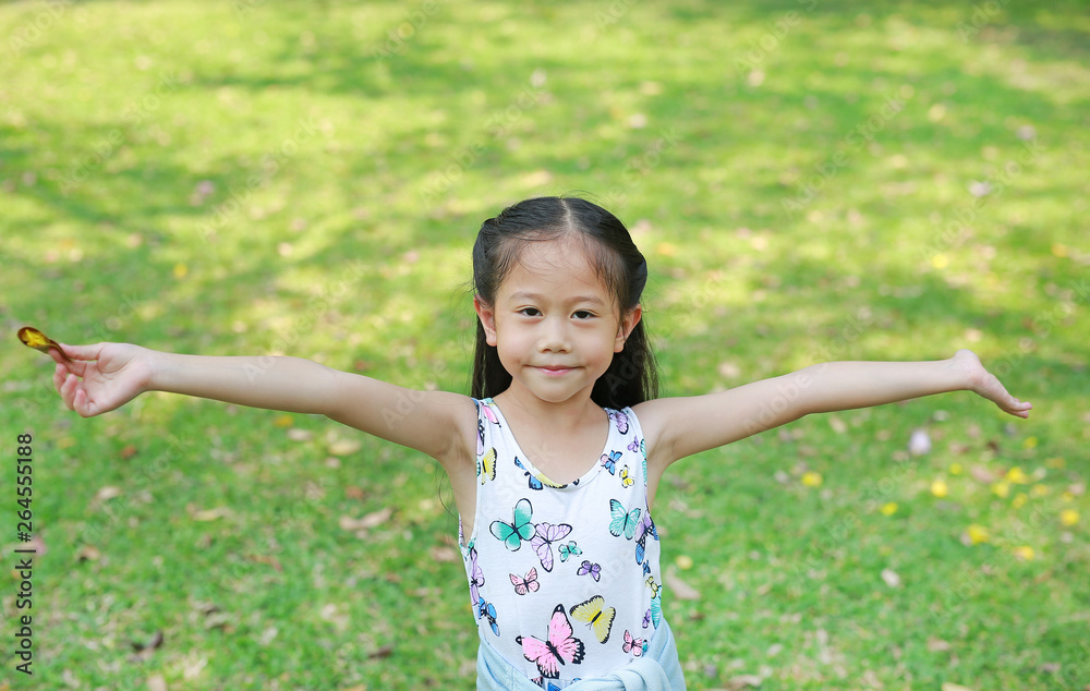 Smiling little Asian child girl opened her hands in the summer garden. Smiling little Asian child girl opened her hands in the summer garden.