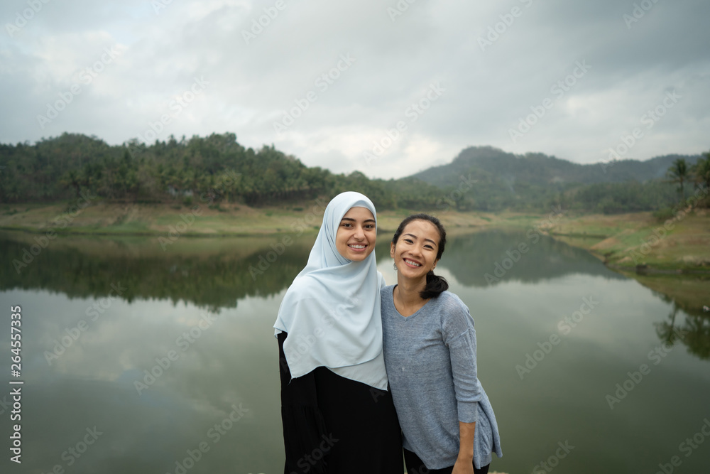 Fototapeta premium asian and muslim middle eastern woman friend together smiling to camera