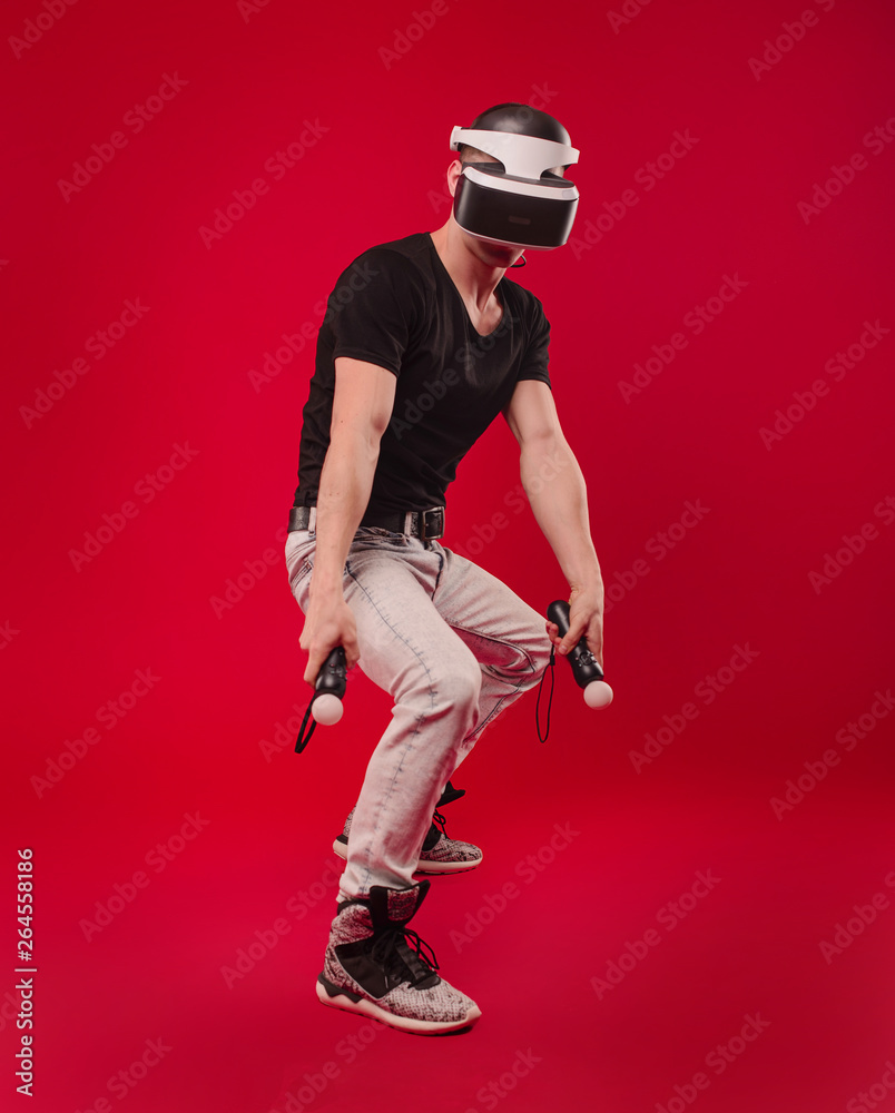 Man wearing virtual reality goggles. Studio shot, red backgroun Man wearing virtual reality goggles. Studio shot, red backgroun