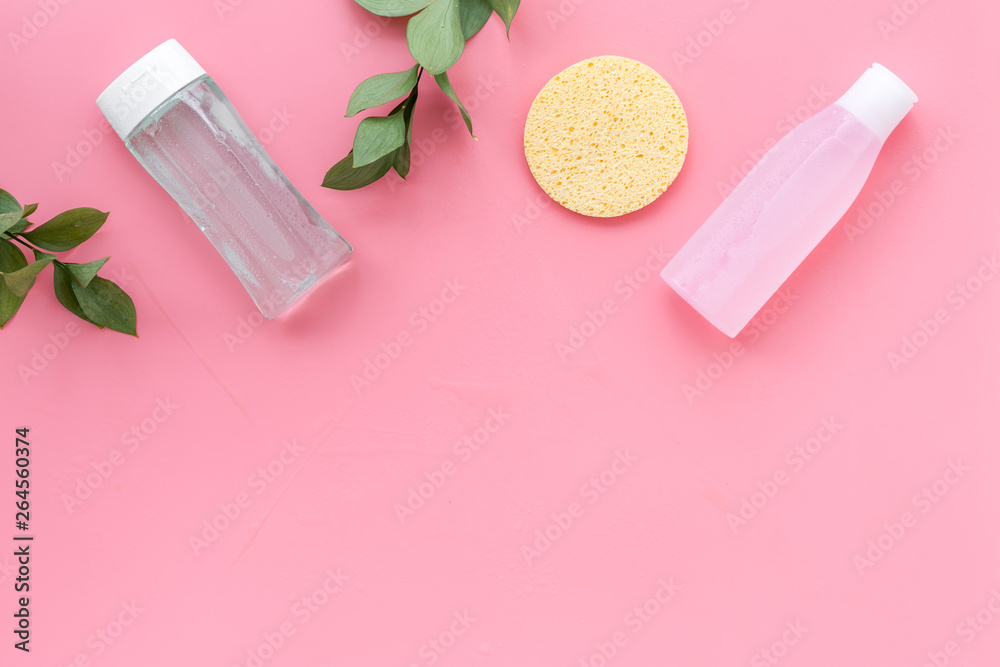 facial tonic, lotion and sponge for face care and plant on pink background top view mock up