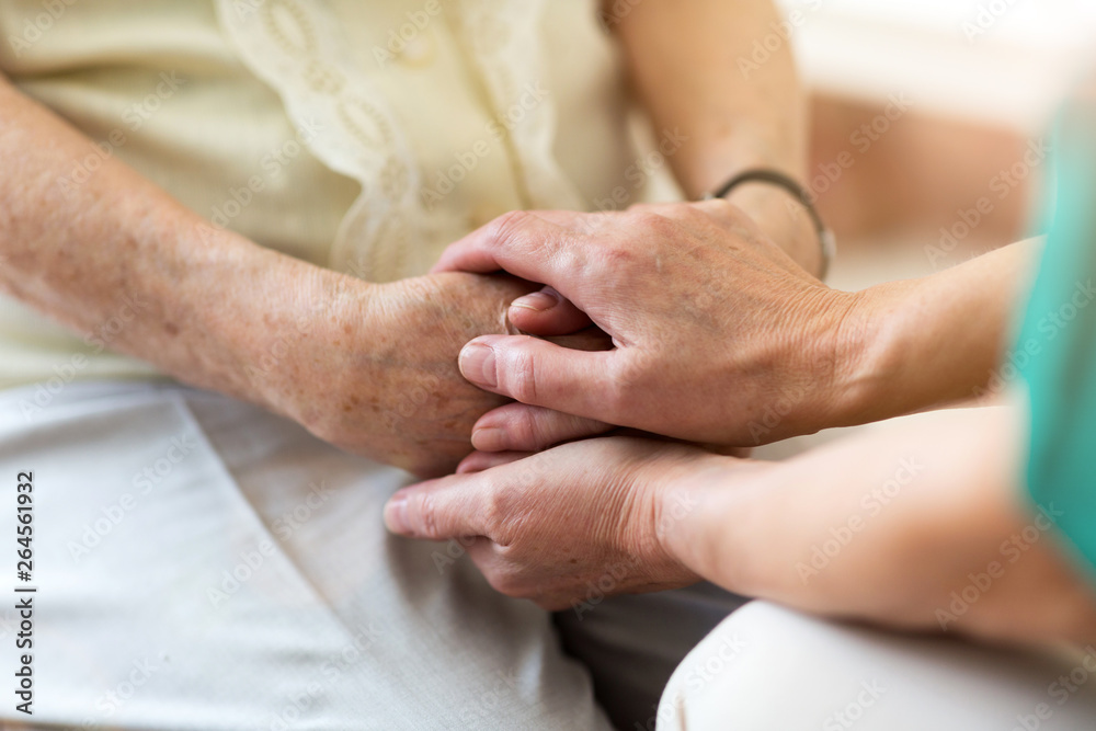 Nurse consoling her elderly patient by holding her hands Nurse consoling her elderly patient by holding her hands
