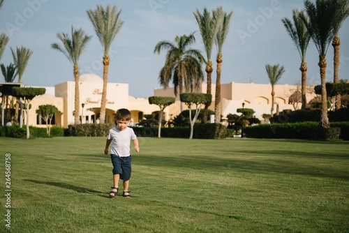 Cute boy runs on a green lawn playing catch-up in nature on a Sunny day.