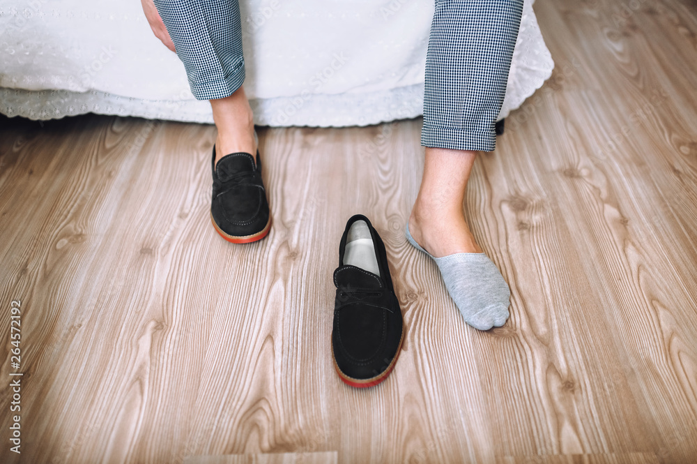 The groom sits and puts his shoes on the charges. Morning groom. Wedding details. Concept and composition. The groom sits and puts his shoes on the charges. Morning groom. Wedding details. Concept and composition.