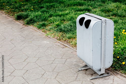 grey metal tresh bin near green grass on alley. photo
