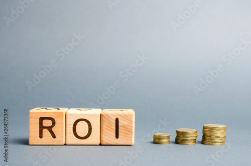 Wooden blocks with the word ROI and coins. High level of business profitability. Return on investment, invested capital, rate. Success. Growth. Profitability. Analytics. photo
