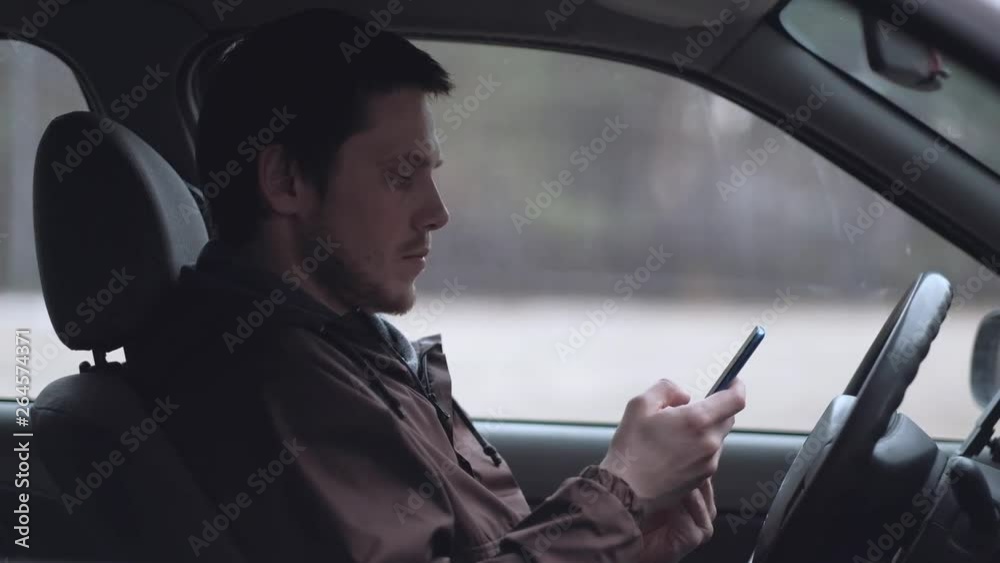 A young man use smartphone, sitting in the cabin of car. Slowmotion. A young man use smartphone, sitting in the cabin of car. Slowmotion.