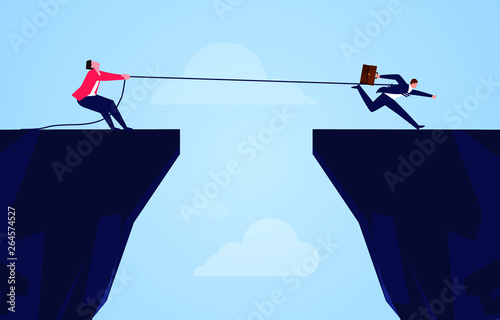 Businessman uses a rope to pull his companion to the cliff