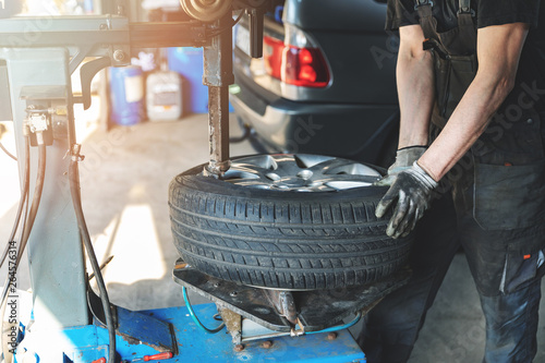 car mechanic changing tire on the rim in service garage