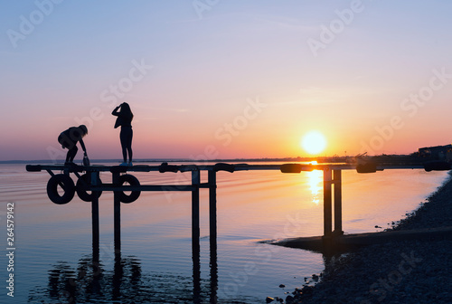 figures of people on the bridge at sunset.