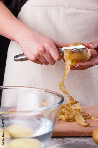 A young woman in an apron peeling potatoes