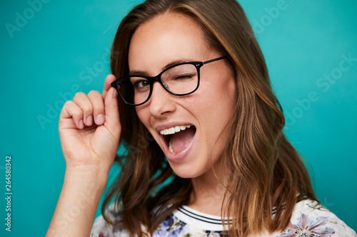 Winking girl in glasses looking at camera, studio