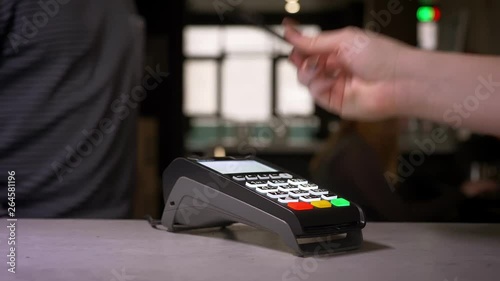 Close-up shot of woman using terminal and credit card performs contactless paypass payment. photo