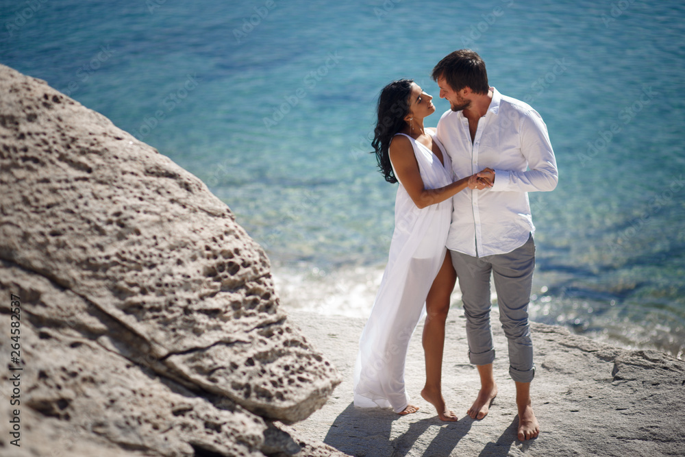 Perfect couple portrait, standing on stone beach behind mediterranean sea, honeymoon in Greece. Perfect couple portrait, standing on stone beach behind mediterranean sea, honeymoon in Greece.