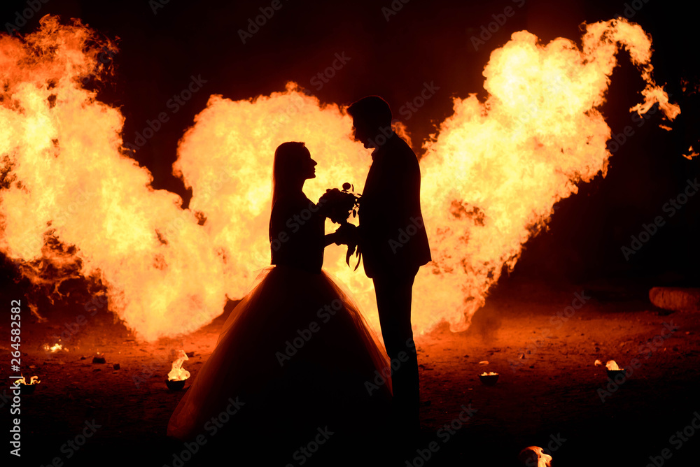 Wedding couple with skull face art is standing in the dark