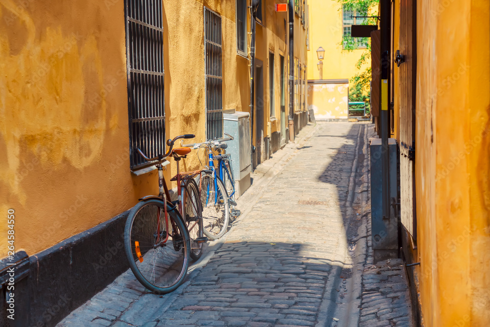 The narrow cobblestone street with a bicycle and yellow medieval houses of Gamla Stan historic old center of Stockholm at summer sunny day.