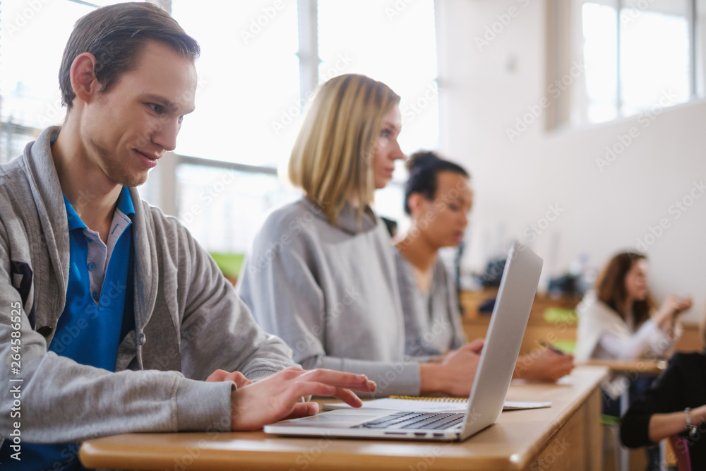 Man with laptop among students in an auditorium