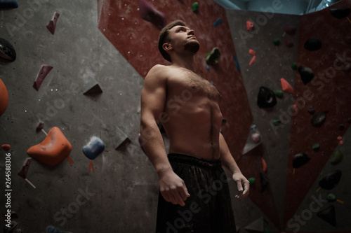 Obraz na plátne Athletic man stretching before climbing in a bouldering gym