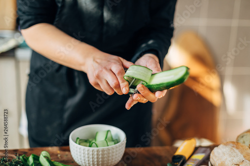 Female chef peeling skin of a cucumber photo