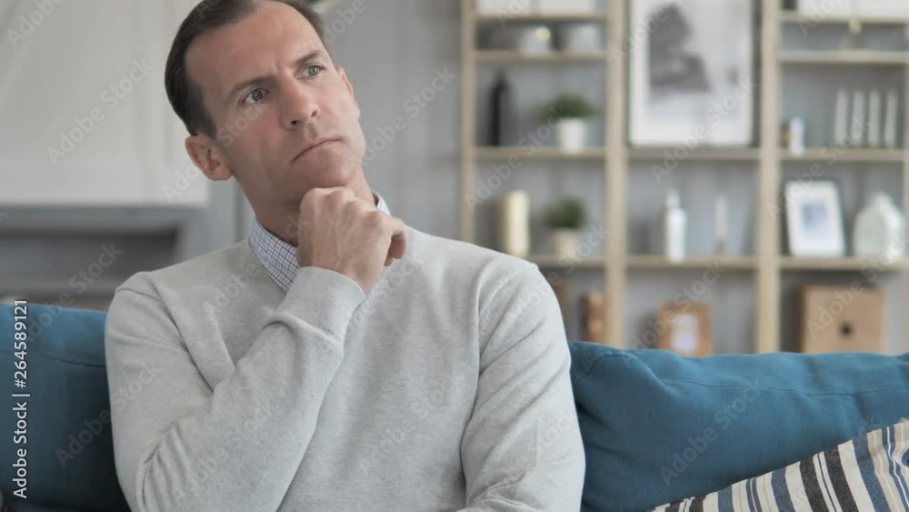 Middle Aged Man Thinking New Idea while Sitting on Couch in Creative Office Middle Aged Man Thinking New Idea while Sitting on Couch in Creative Office