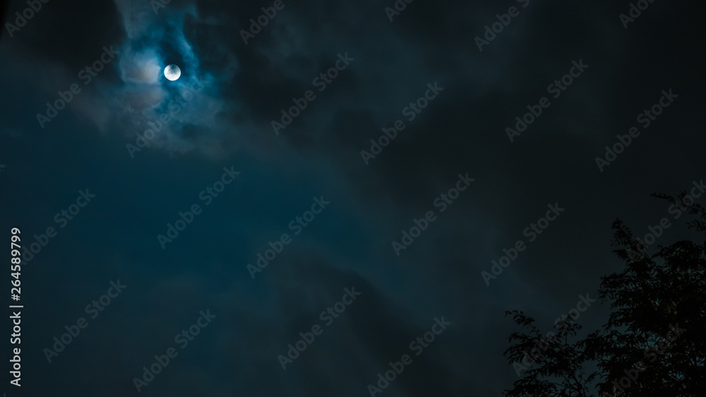night sky and astronomy on blue background concept from full moon behind the cloud during watch spectacular winter solstice event in december of 2018