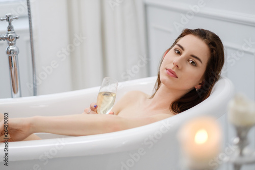 Woman laying in a bath with glass of champagne