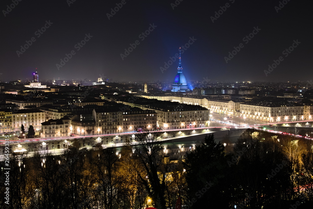 Aerial night dark view on Turin city center, the Mole Antonelliana is illuminated by special blue lights in a foggy night Aerial night dark view on Turin city center, the Mole Antonelliana is illuminated by special blue lights in a foggy night