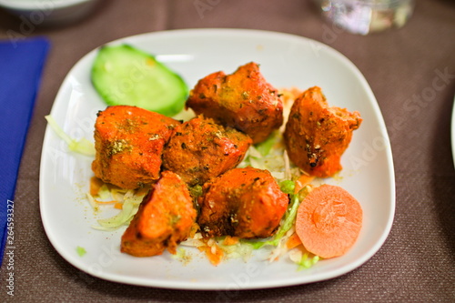 Close up on a tandoori chicken plate. It is a chicken dish prepared by roasting chicken marinated in yoghurt and spices in a tandoor, a cylindrical clay oven. 
