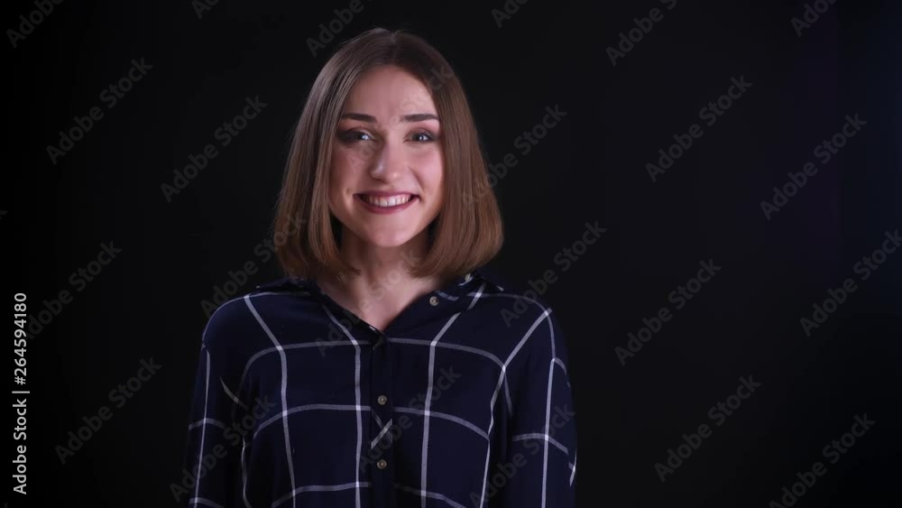 Closeup shoot of young pretty short haired female getting excited and surprised looking straight at camera with background isolated on black Closeup shoot of young pretty short haired female getting excited and surprised looking straight at camera with background isolated on black