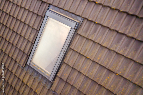 Close-up of new attic plastic window installed in shingled house roof. Professionally done building and construction work, roofing and installation concept.